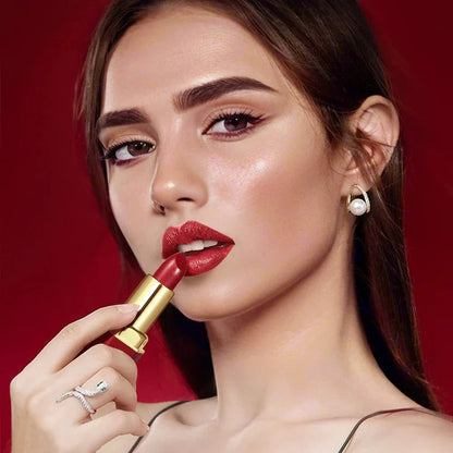 Donna che applica rossetto a tubo rosso con barra d'oro e texture opaca su labbra vellutate
