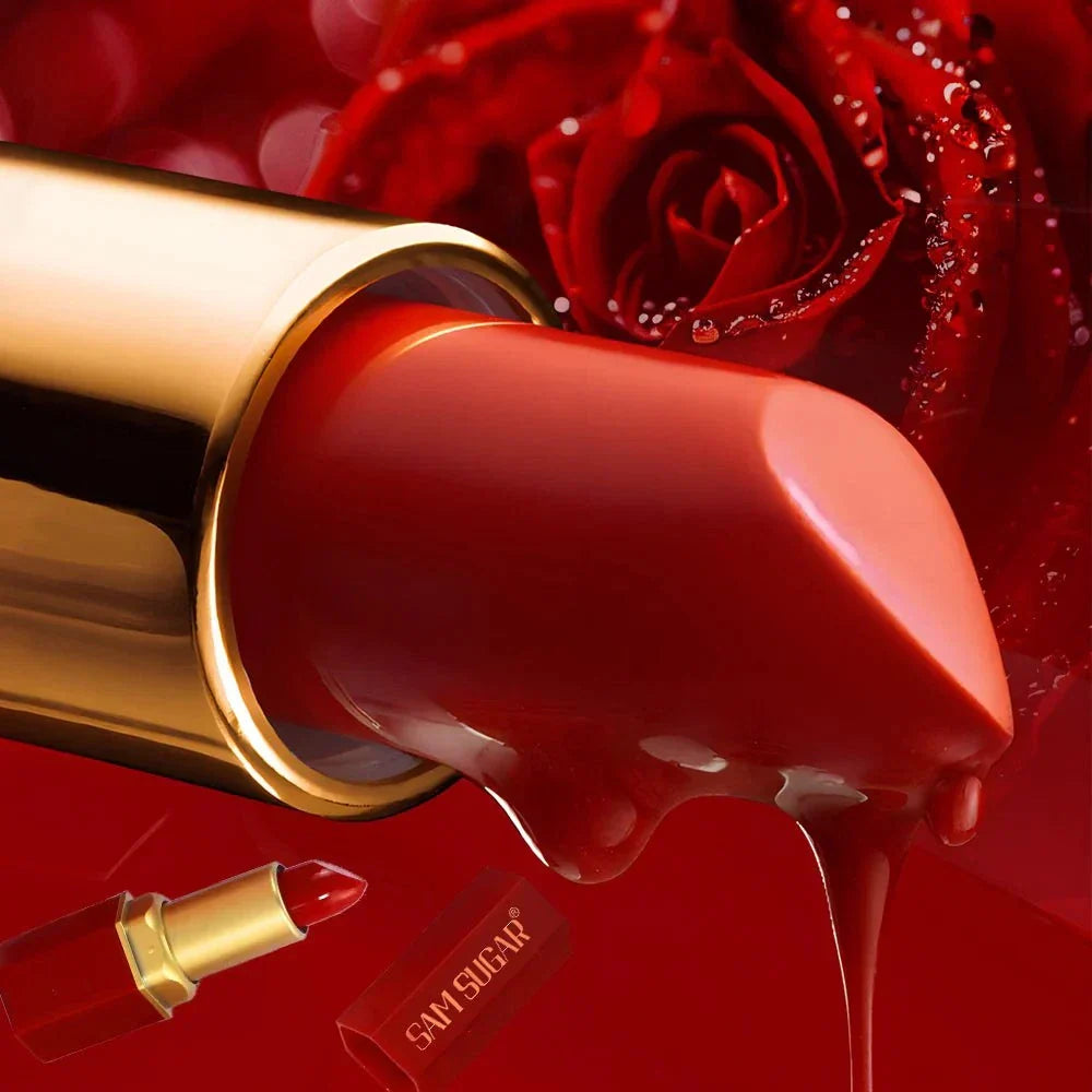 Rossetto a tubo rosso opaco con barra dorata e glitter perlescenti su sfondo di rose rosse